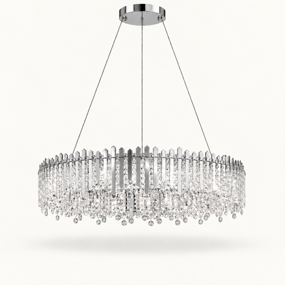 A modern circular chandelier with a polished silver-tone metal frame and numerous clear crystal prisms and hanging drops, suspended by thin cables from a round ceiling canopy against a light off-white background.